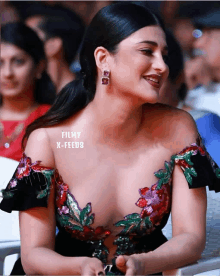 a woman in a very revealing dress is smiling and has filmy x-feeds written on her chest