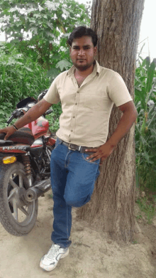 a man leans against a tree while standing next to a motorcycle that says bajaj