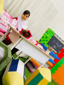 a little girl sits at a desk with a hello kitty backpack on it