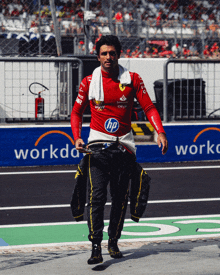 a man in a red hp shirt walks down a track