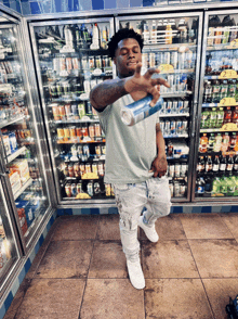 a man is standing in front of a refrigerator holding a can of gatorade