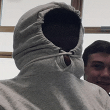 a person wearing a grey hoodie with a hole in the middle