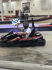 a man driving a go kart with a birthday party poster behind him