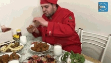 a man in a chef 's uniform is sitting at a table with plates of food and a glass of milk