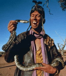 a man wearing a helmet and goggles is holding a large snake