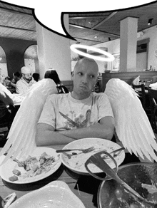 a man with angel wings and a halo on his head sits at a table