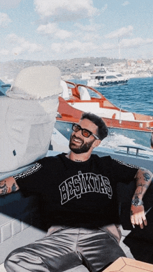 a man wearing a besiktas shirt sits on a boat in the water