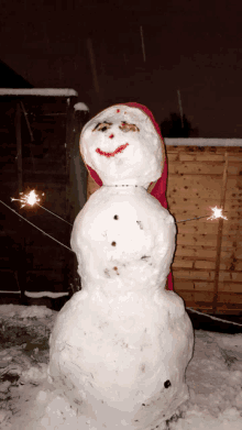 a snowman with a red scarf around his head and sparklers on his arms