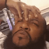 a man with a beard is holding his hands to his face .