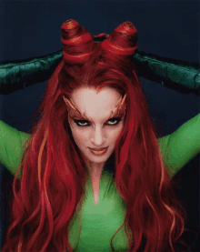 a woman with red hair and green gloves is wearing poison ivy costume