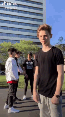 a group of young men are standing in front of a building with tiktok written on the bottom of the screen