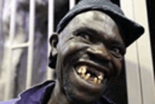 a man with a hat and a beard is smiling with a very large smile .