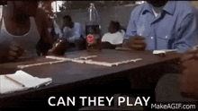 a group of people are sitting at a table playing dominoes with a coca cola bottle in the background .