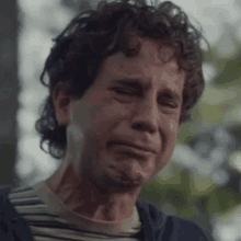 a man with curly hair is crying with his eyes closed .