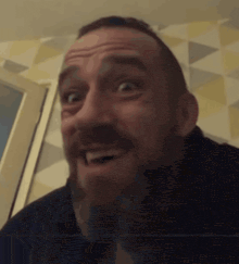 a man with a beard is making a funny face in front of a geometric wall .