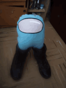 a blue among us stuffed animal is sitting on a pair of black boots