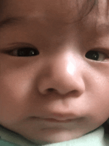 a close up of a baby 's face with a white spot on the nose