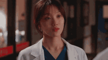 a close up of a woman in a lab coat and scrubs .