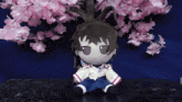 a stuffed animal with a bunny ear is sitting in front of a cherry blossom tree