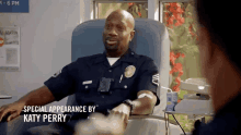 a police officer is sitting in a hospital chair talking to a woman