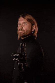 a man with a beard wearing a black jacket and gloves