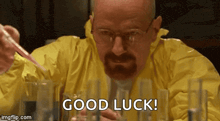 a man in a yellow suit is holding a pipette and saying good luck