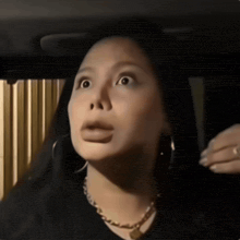 a woman with a surprised look on her face is wearing hoop earrings and a necklace