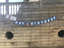 a happy birthday banner hangs from a wooden wall