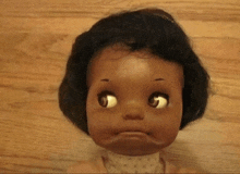 a close up of a doll 's face on a wooden floor