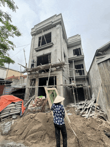 a woman wearing a hat stands in front of a building under construction