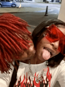 a man with red hair is kissing a woman with red sunglasses