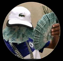 a man wearing a white hat with a crocodile on it is holding a fan of 100 bills