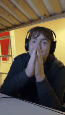 a young man wearing headphones is sitting at a desk with his hands folded