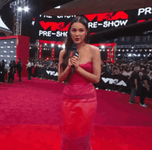 a woman in a pink dress is standing on a red carpet in front of a sign that says pre-show