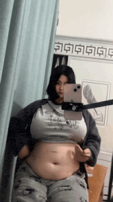 a woman is taking a selfie in front of a mirror with chinese writing on the wall behind her