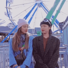 two women standing next to each other in front of a ferris wheel that says ' fun ' on it