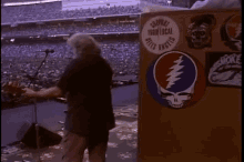 a man is standing in front of a podium with a grateful dead sticker on it in a stadium .