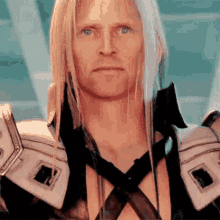 a man with long blonde hair and blue eyes is wearing a black and white outfit and looking at the camera .