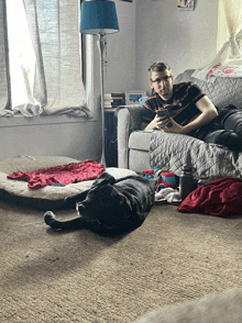 a man is sitting on a couch with a dog laying on the floor