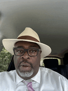 a man wearing a hat and glasses is sitting in the back seat of a car