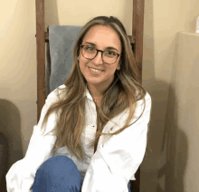 a woman wearing glasses and a white shirt is smiling for the camera