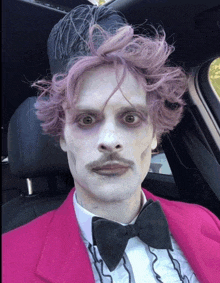 a man with purple hair and a mustache is wearing a pink suit and bow tie