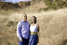 a man and woman are standing in a field of tall grass