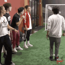 a group of people are standing in front of a soccer goal and one of them is wearing a white adidas shirt