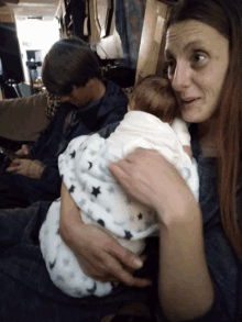 a woman is holding a baby wrapped in a star blanket