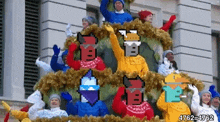 a group of people are standing on top of a christmas tree with their arms in the air .