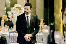 a man in a suit and tie is standing in front of a table with flowers on it