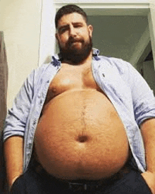 a man with a beard and a very large belly is standing in a room .