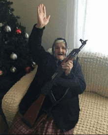 an elderly woman sitting on a couch holding a gun and waving