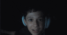 a young boy wearing headphones is smiling in the dark